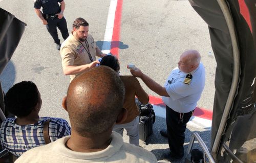 Passengers have their temperature taken as their leave the plane.