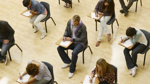 Studenti universitari mentre sostengono un esame in un'aula magna.