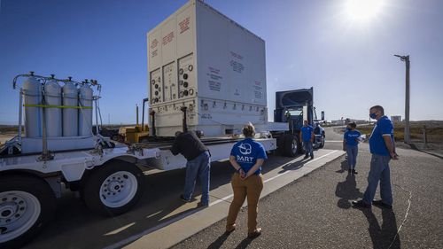 DART team members stand outside Astrotech Space Operations processing facility with the shipment container holding the DART spacecraft. DART moved to SpaceX's payload processing facility late October.
