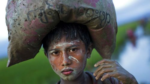A Rohingya boy, an ethnic minority from Myanmar, carries a sack of belongings on his head and walks through rice fields after crossing over to the Bangladesh side of the border near Cox's Bazar's Teknaf area. (AP)