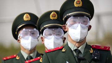 Chinese paramilitary police wearing goggles and face masks march in formation.