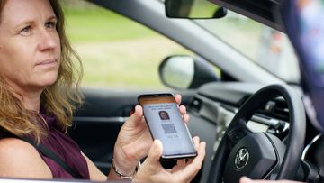 A driver presenting their digital licence app to a Queensland police officer.