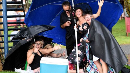 Racegoers get caught out in a spurt of heavy rain during the Ballarat Cup Day at the Ballarat Turf Club in Ballarat, Saturday, November 25, 2017.