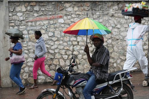 Um motociclista usa guarda-chuva durante uma chuva leve no bairro de Petion-Ville, em Porto Príncipe, Haiti, terça-feira, 28 de outubro de 2025, enquanto o furacão Melissa passa pelo Caribe. (Foto AP/Odelyn Joseph)
