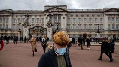 A man wears a face mask as he walks past Buckingham Palace as the outbreak of coronavirus intensifies