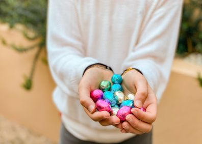 little girl holding chocolate easter eggs with her hands