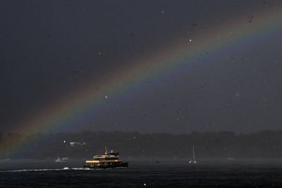 Brief sunshine in between storms brought out a rainbows above a Sydney ferry.