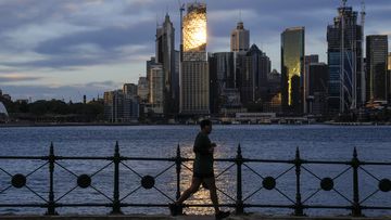 A man runs around the waterfront of Sydney Harbour as the sun rises in Sydney,