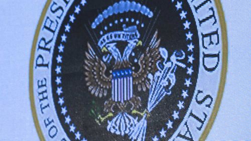 The seal showed a two-headed eagle clutching golf clubs and money, instead of arrows and an olive branch. The stars on the American shield were replaced with USSR-style hammers and sickles.