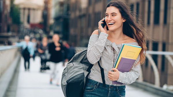 Smiling student walking and talking on the phone