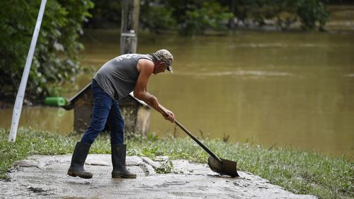 Junior Bowling shovels mud and silt from receded floodwaters in Jackson, Ky., Friday, July 29, 2022. Floodwater from the North Fork of the Kentucky River came within inches of getting inside his home. (AP Photo/Timothy D. Easley)