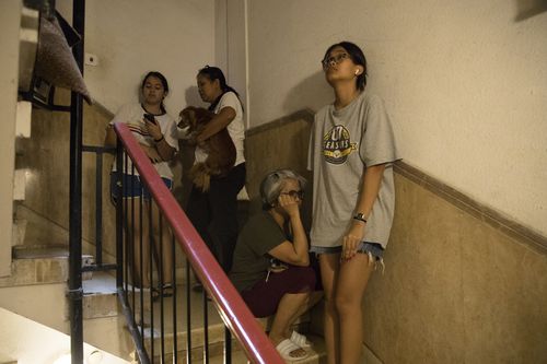 People hide in a building staircase as sirens are heard in on October 7, 2023 in Tel Aviv, Israel. 