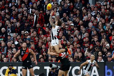 Jamie Elliott of the Magpies takes a spectacular mark over Ben McKay of the Bombers during the annual Anzac Day clash.