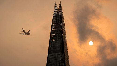 A plane flies by the Shard building in central London during an eerie phenomenon causing the sky to turn red. (AAP)