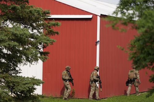 Members of law enforcement agencies search for shooting suspect, Vance Boelter, at a house Sunday, June 15, 2025, in Belle Plaine, Minn. (AP Photo/George Walker IV)