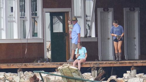 A girl salvages a bell from the main building at Camp Mystic along the banks of the Guadalupe River after a flash flood swept through the area.