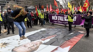 A protestor prepares to jump on a banner with the image of Turkish President Recep Tayyip Erdogan during a demonstration organised by The Kurdish Democratic Society Center in Sweden.