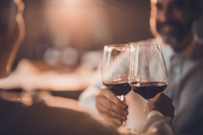 Close up of a couple toasting with red wine in a restaurant.