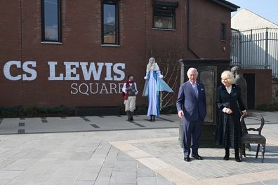 Prince Charles, Prince of Wales and Camilla, Duchess of Cornwall pose with one of the bronze sculptures commemorating the Belfast-born author, CS Lewis as performers dressed as Narnia characters look on at CS Lewis Square on day 2 of their visit to Northern Ireland on March 23, 2022 in in Belfast, Northern Ireland. 