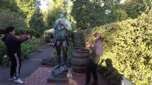 Geelong-based music duo 'Divide and Dissolve' filmed themselves using water pistols containing their own urine to spray Australian historical colonial monuments around the Melbourne CBD. Picture: YouTube/Divide and Dissolve.