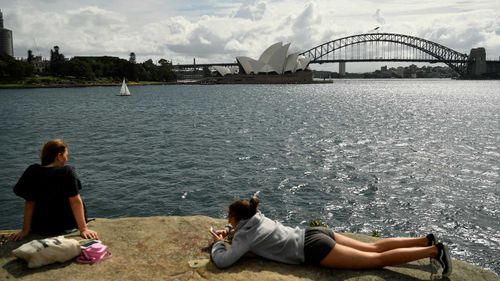 Tourists lie in the sun in Sydney Harbour.