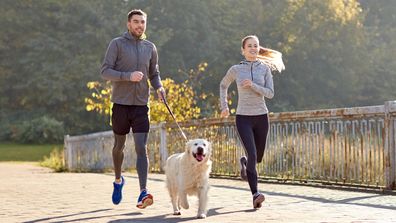 Man and woman running with dog on lead 