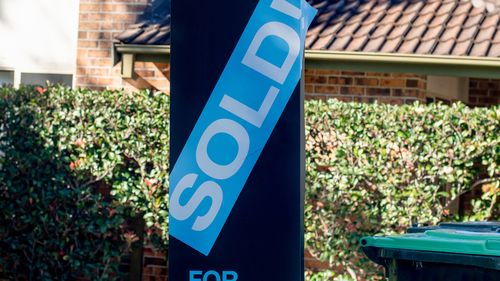 Placa de venda perto de prédio residencial com um adesivo vendido 