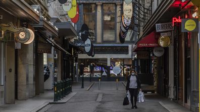 A lone shopper is seen carrying shopping bags as she walks down the usually busy Degraves Street laneway fame for its cafes and coffee as lockdown of Melbourne forces people to stay at home if not working due to the continuing spread of COVID-19. (Asanka Brendon Ratnayake)