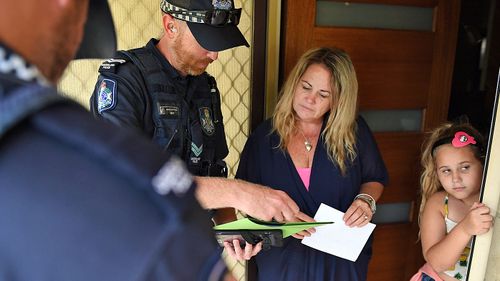 Resident Janelle Eade signs a disclaimer after advising Police and SES that she will not evacuate her house, situated in a low lying area of Ayr, south of Townsville. (AAP)