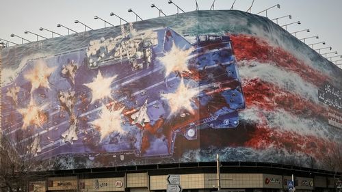 A billboard depicting a damaged US aircraft carrier with disabled fighter jets on its deck and a sign reading in Farsi and English, "If you sow the wind, you'll reap the whirlwind," is seen at Enqelab-e-Eslami (Islamic Revolution) Square in Tehran. Iran has blamed foreign powers, including the USA, for the recent unrest and protests.
