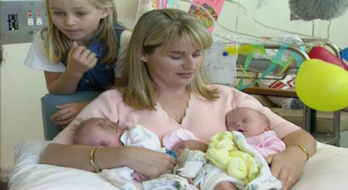 Trish Dixon nurses her newborn triplets  as big sister, Candice, looks on. (Supplied)