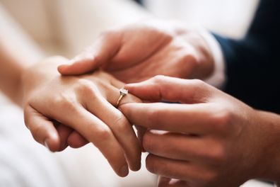 Cropped shot of an unrecognizable groom putting a diamond ring on his wife's finger during their wedding