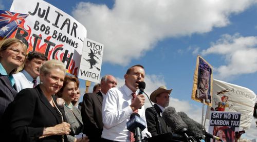 Then opposition leader Tony Abbott in front of a "ditch the witch" poster at a rally outside Parliament House in 2011