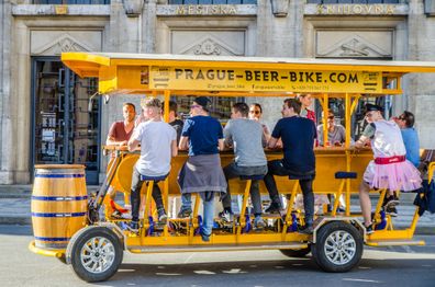 Yellow beer bike serving as guided tour while drinking beer in going away on downtown Prague street during day of springtime