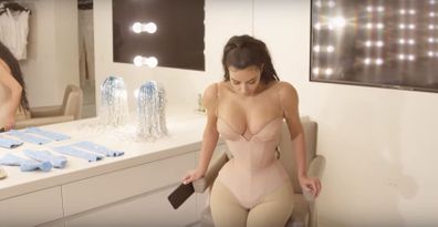 Kim Kardashian half sitting in corset