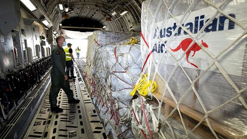 Air Force Load Master Corporal Dale Hall, from No. 36 Squadron, inspects pallets of Australian Aid bound for Tonga loads inside a C-17A Globemaster III strategic airlift aircraft at RAAF Base Amberley.