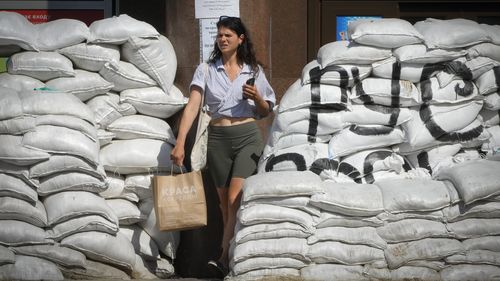 A woman passes by sandbags that were set to protect against Russian shelling in central Kyiv, Ukraine, Tuesday, June 7, 2022. (AP Photo/Efrem Lukatsky)