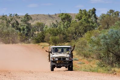 Family in four-wheel-drive vehicle, Mereenie-Watarrka Road, Red Centre, Australia.