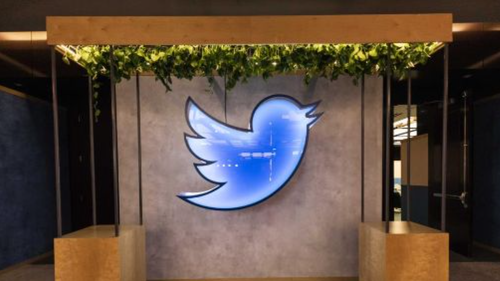 A neon-blue sign of the twitter logo
