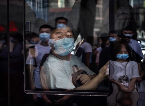 A commuter wears a mask to protect against COVID-19 as he sits on a public bus in Beijing.