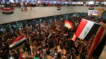 Protesters wave flags inside the Iraqi parliament. (AFP)