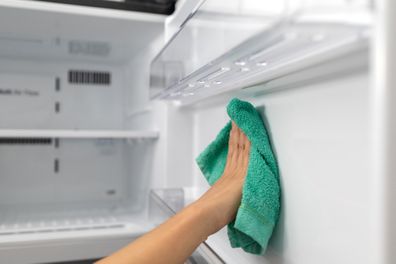 Fridge interior being cleaned with a cloth