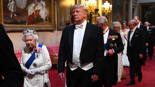 The Queen and Donald Trump enter the royal banquet.