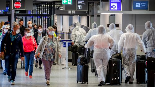 Passengers who have just arrived at the airport walk past crew members of South African Airways, right, on their way to the security check at the airport in Frankfurt, Germany.