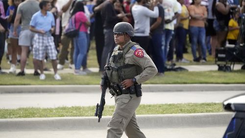 یک افسر مجری قانون در حالی که مردم از یک مرکز خرید که در آن تیراندازی شنبه، 6 می 2023، در تگزاس رخ داد، تخلیه می‌شوند، راه می‌رود. 