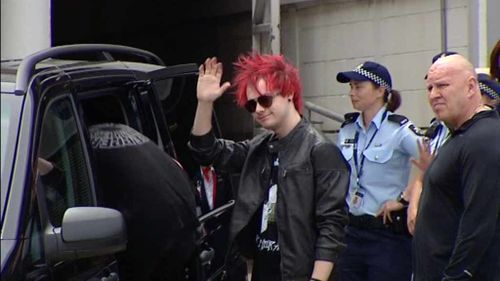 Michael Clifford from 5 Seconds of Summer waves to fans at Sydney Airport. (9NEWS)