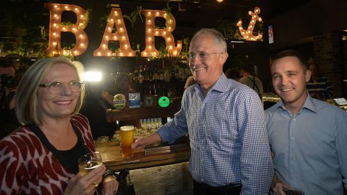 Prime Minister Malcolm Turnbull, his wife Lucy and Assistant Minister for Innovation Wyatt Roy have a drink at a Politics in the Pub event in Sandstone Point. (AAP/Lukas Coch)