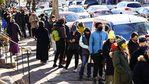 City residents wait in a line extending around the block to receive free at-home rapid COVID-19 test kits in Philadelphia.