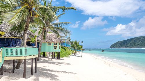 View along Lalomanu Beach, Upolu Island, Samoa, South Pacific, of colorful Samoan beach fale huts that are an alternative to hotel or resort accommodation