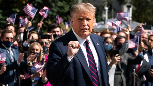 US President Donald Trump gestures as White House interns cheer him on as he leaves the White House residence for Marine One on the South Lawn 